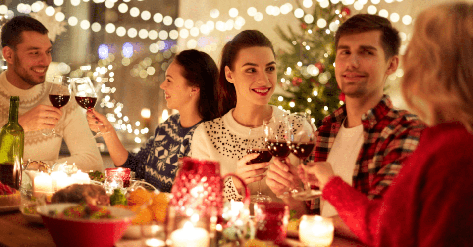 Friends toasting with red wine at a holiday dinner party illustrating how to remove holiday season stains from Long Island homes