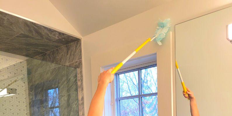 C's house cleaning expert using a Swiffer Extender to remove dust from hard-to-reach places