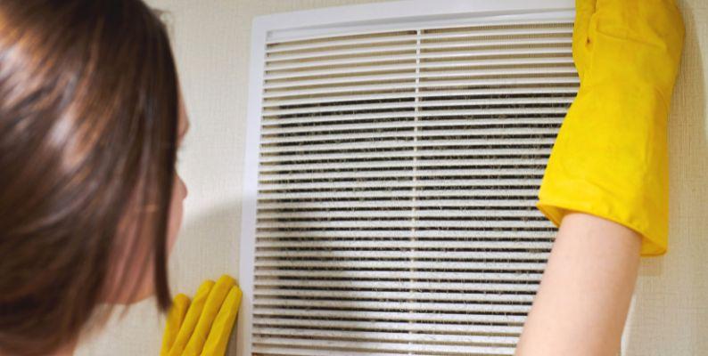 Cleaning professional changing a home's air filter to improve air quality and furnace performance 