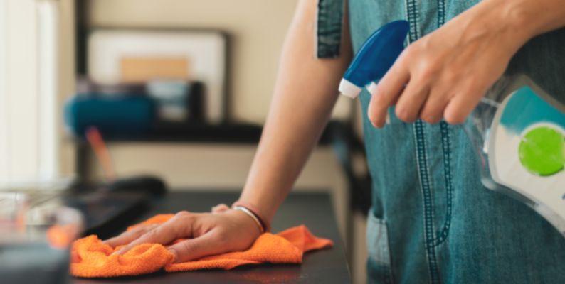 house cleaning professional using a damp microfiber cloth to dust