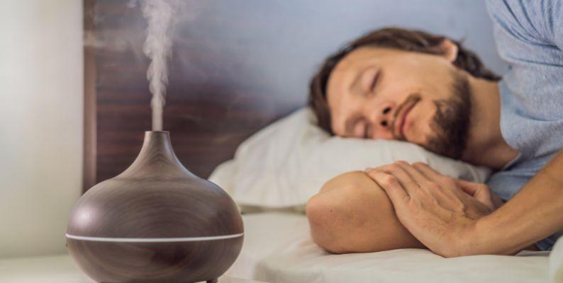 A man sleeping while his bedside air diffuser pumps essential oils into the indoor air