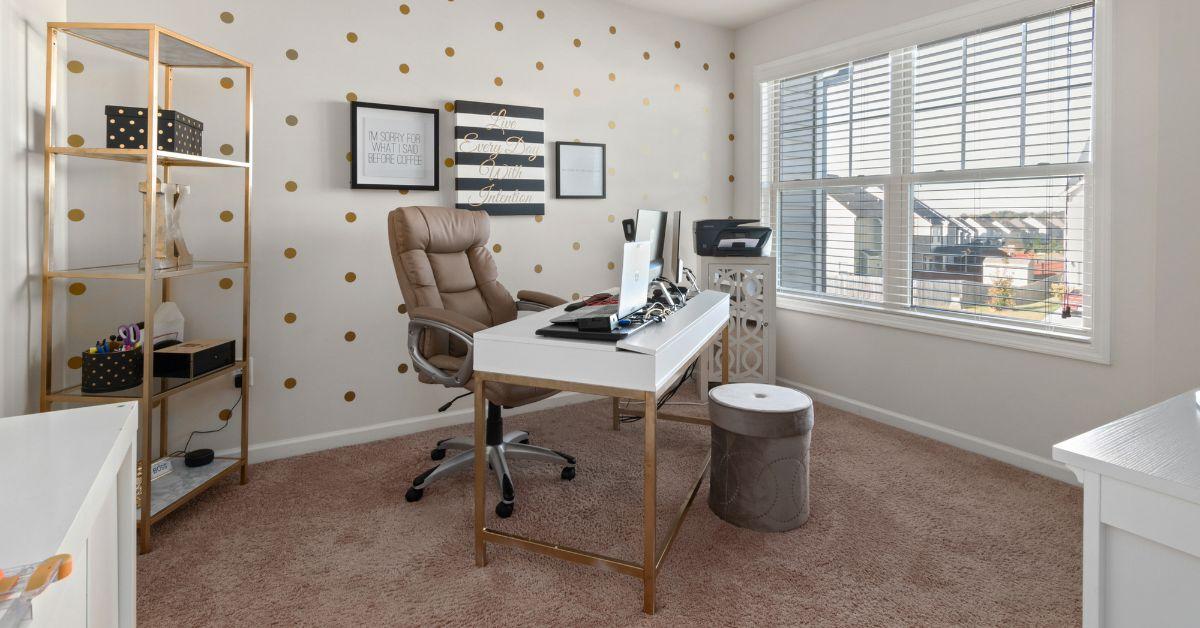A bright, modern workspace featuring a white desk with a laptop, a brown leather ergonomic chair, a gold shelving unit, and a playful gold polka-dot accent wall, showing how to design an efficient and organized home office.